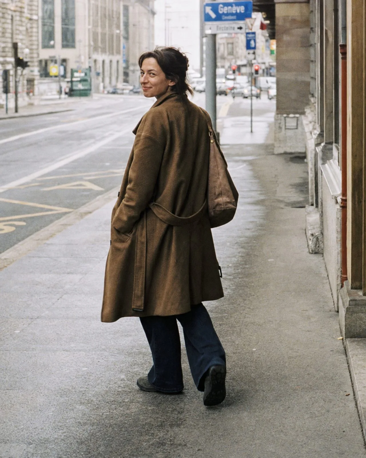 Une femme marche seule dans une rue de Genève, un sourire discret