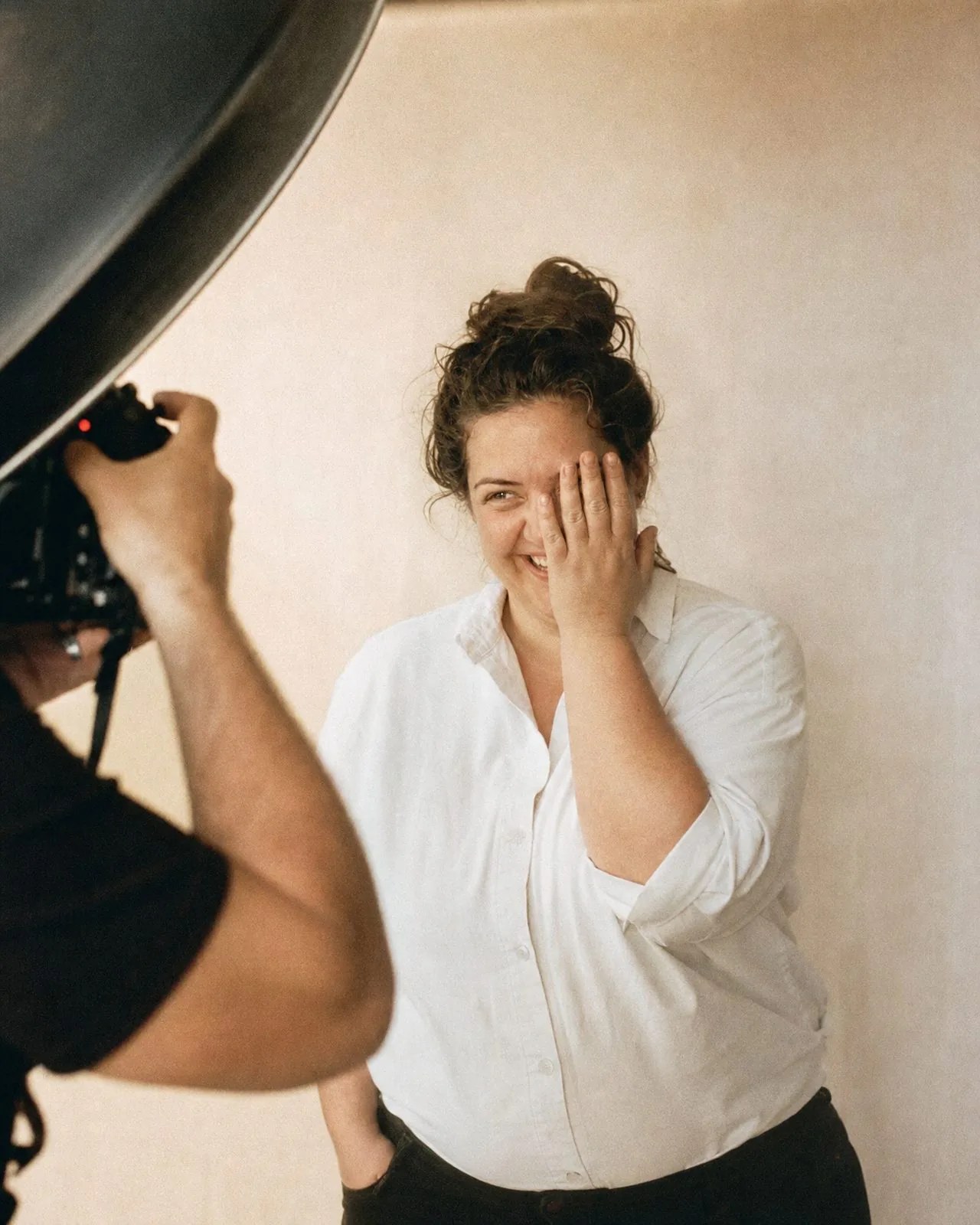 Camille rit de surprise devant l'objectif, une main devant le visage
